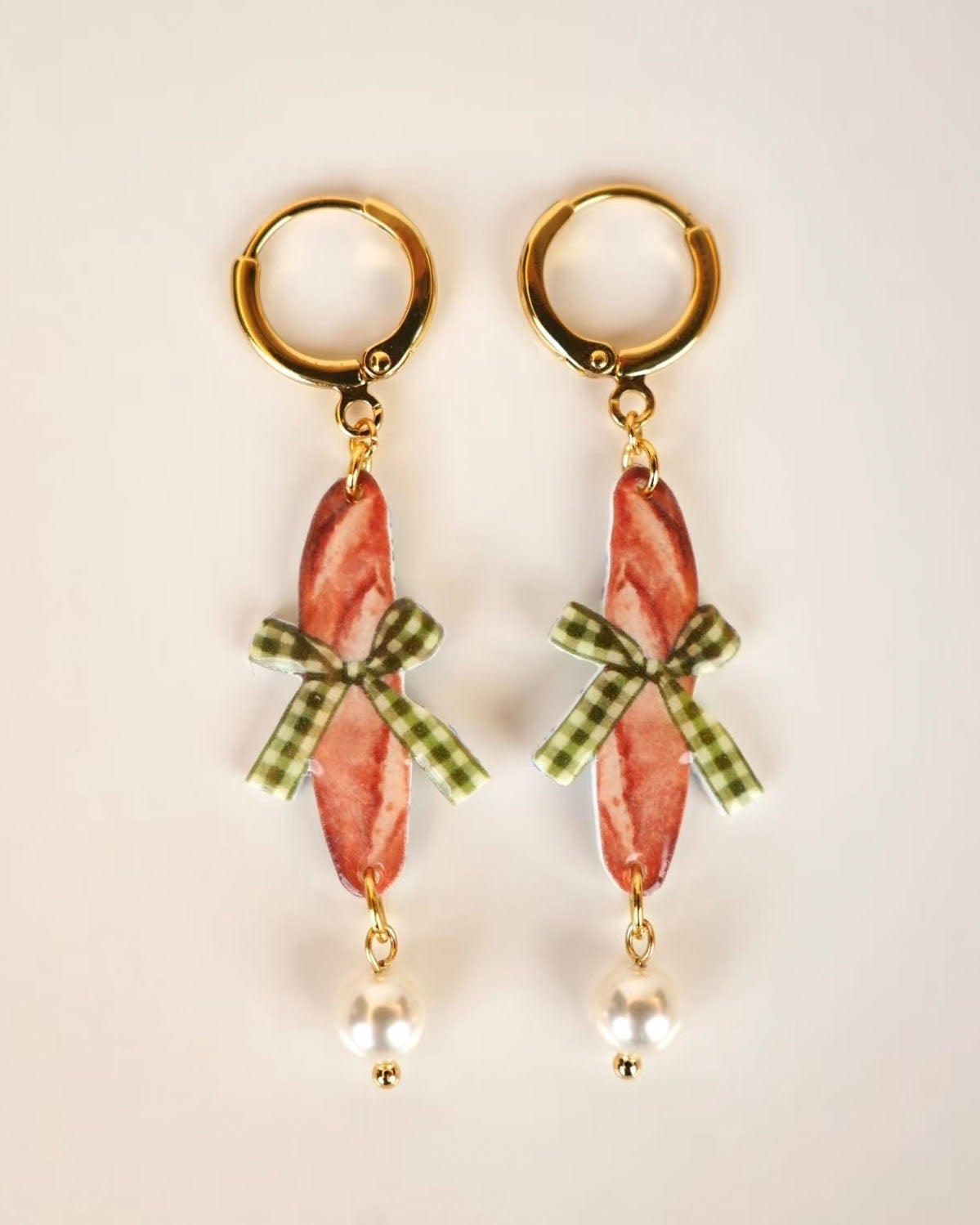 Handgefertigte Playful Drops Ohrringe mit Baguette-Motiv, grüner Schleife und Perle – vor weißem Hintergrund, Luumi Creative Hamburg.