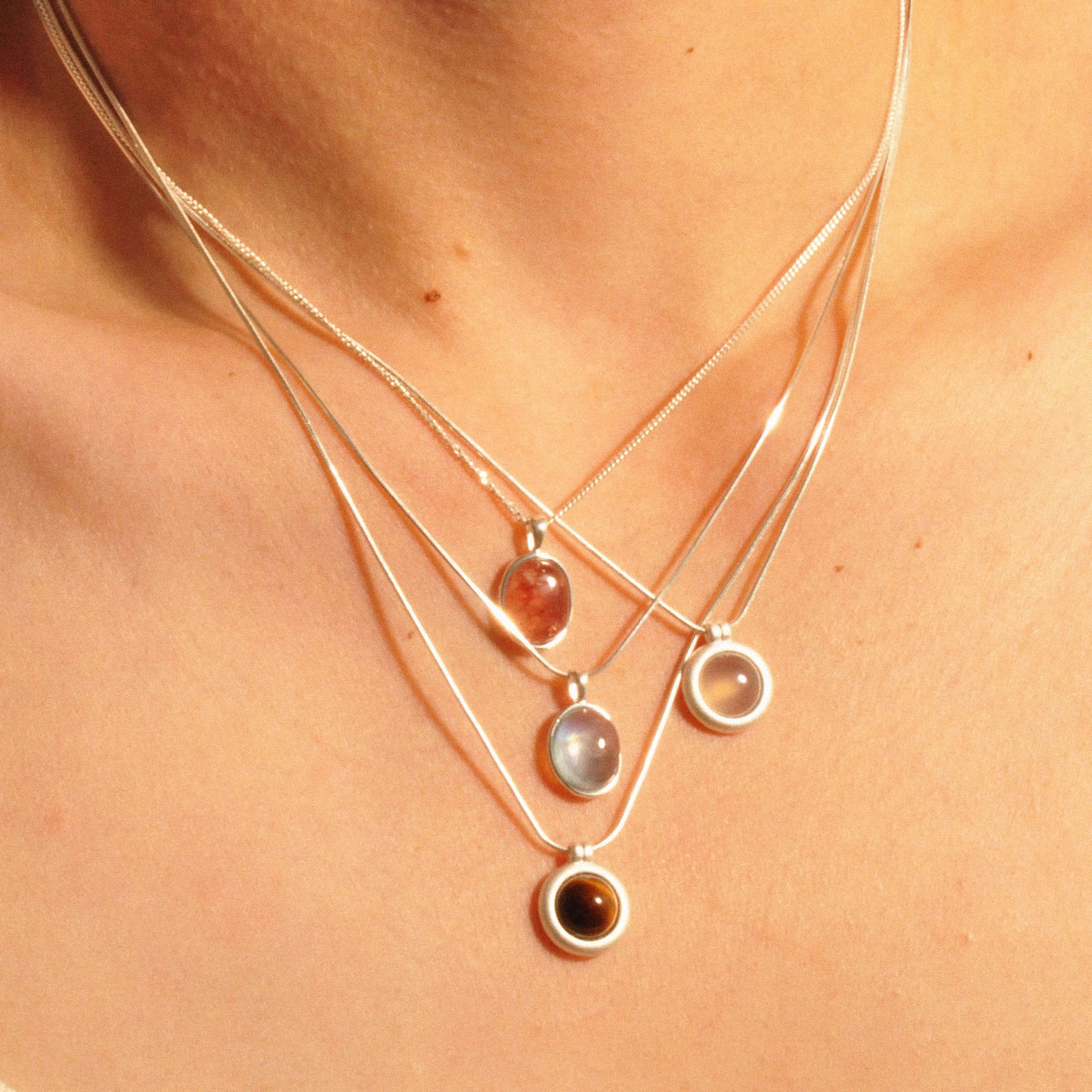 Modell trägt Layering-Halsketten mit Erdbeerquarz, weißem Chalcedon, Tigerauge und Aquamarin.