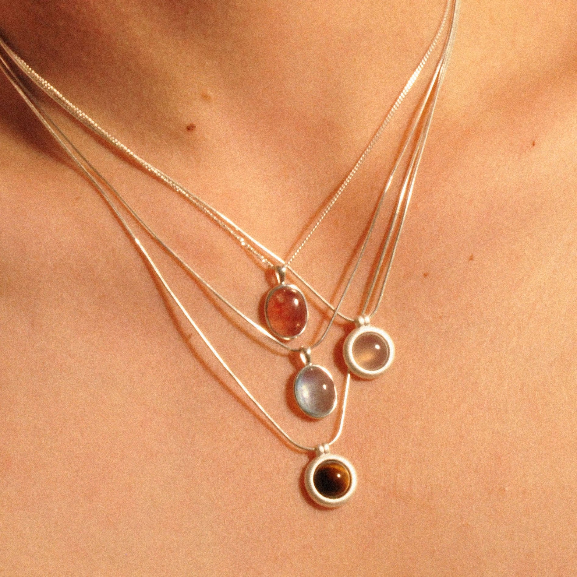 Modell trägt Layering-Halsketten mit Erdbeerquarz, weißem Chalcedon, Tigerauge und Aquamarin.