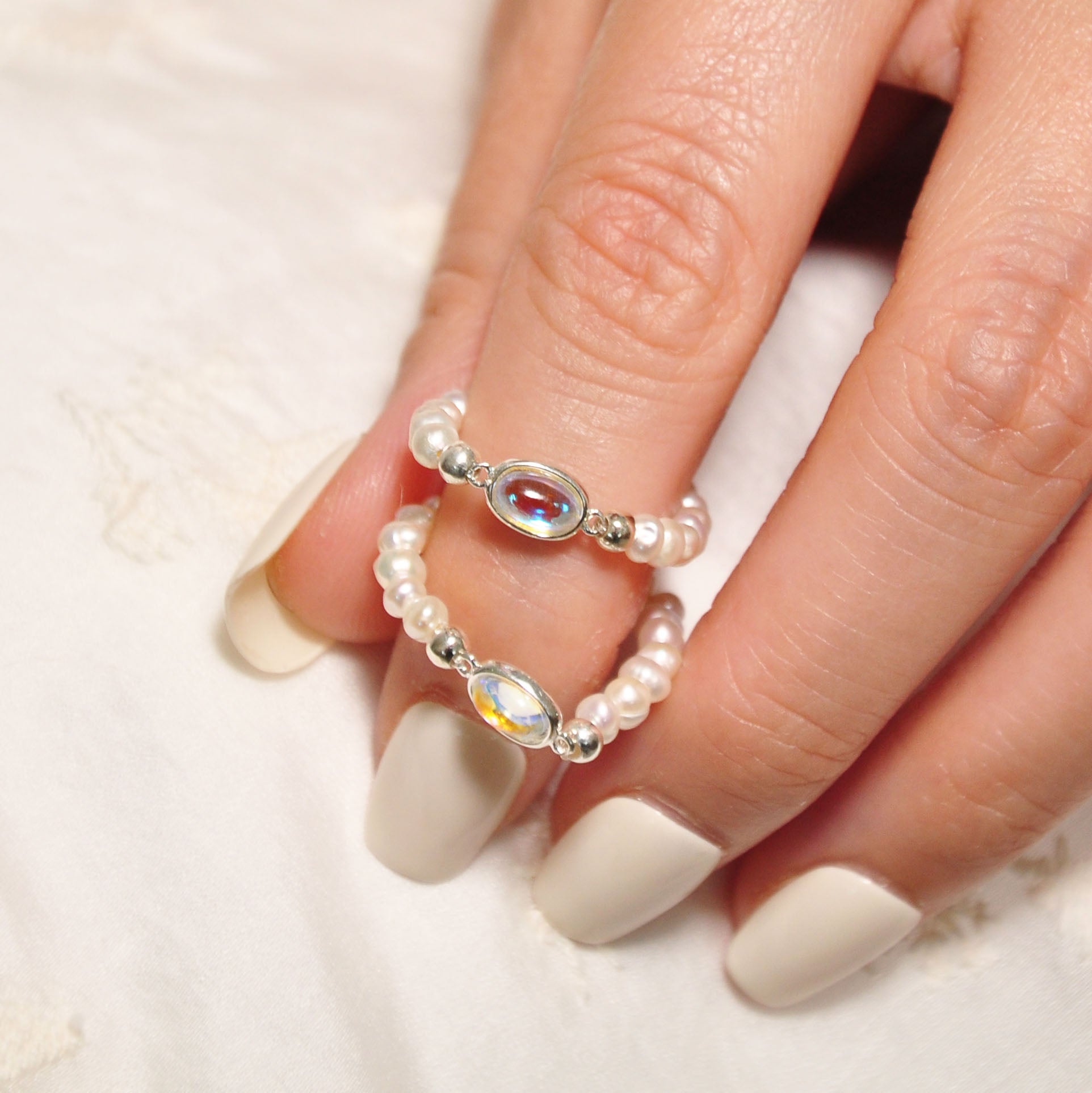 Modell trägt verstellbaren Lunette Ring aus Mondstein, 925er Silber und Süßwasserperlen