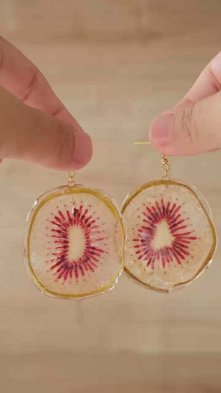 Kurzes Video zeigt handgefertigte Real Kiwi Ohrringe aus echten Kiwi-Scheiben, in der Hand gehalten bei natürlichem Licht – Fruchtschmuck von Luumi Creative Hamburg.