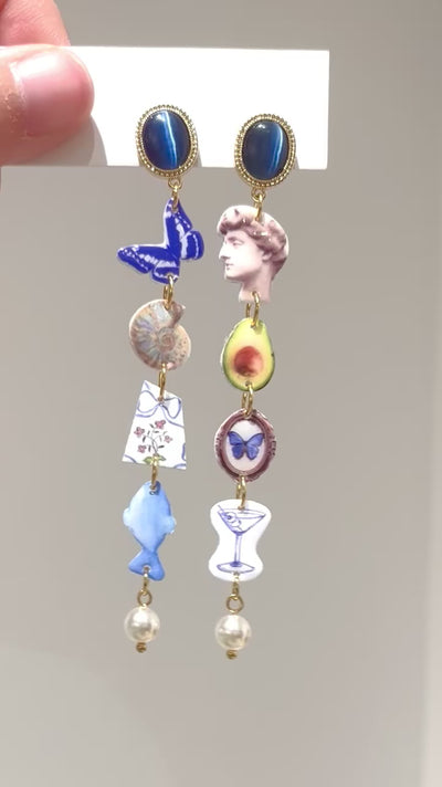 Kurzes Video, das die Playful Drops Ohrringe mit Avocado- und Schmetterlings-Charms zeigt – handgefertigtes Design von Luumi Creative, Hamburg.